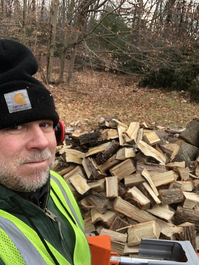 Pocono Firewood owner beside a fresh stack of hardwood